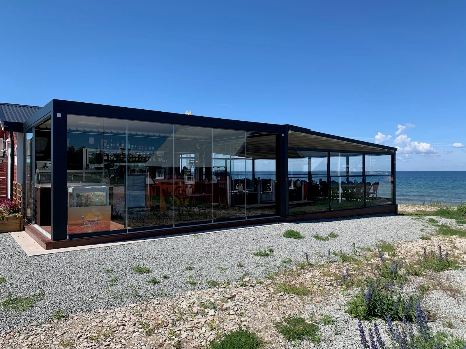 Glasad restaurangpaviljong vid Strandbaden Sandvik med utsikt över havet